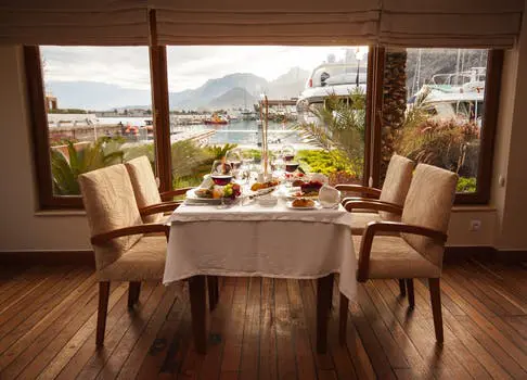 Cozy dining table set for two with a scenic waterfront view.