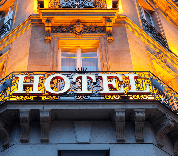 Illuminated hotel sign on a classic building facade at dusk.