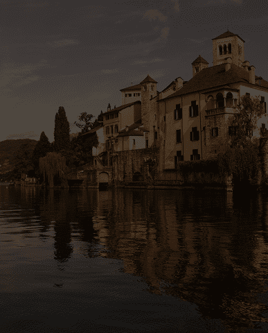 Historic buildings reflecting on calm waters at sunset.