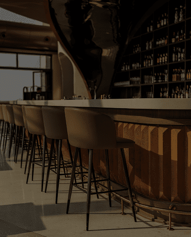 Modern bar with high stools and warm lighting.
