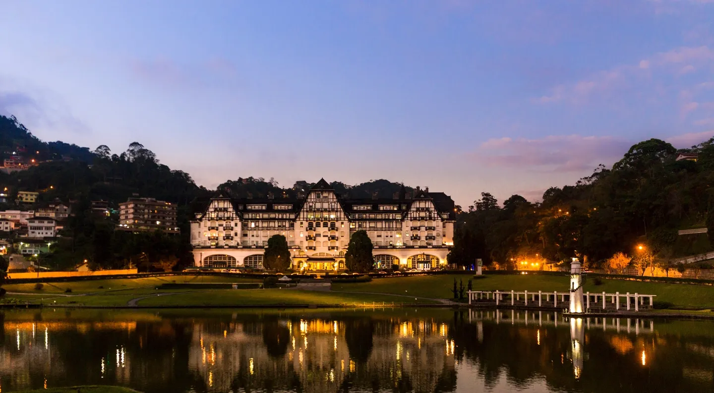 Elegant lakeside hotel illuminated at dusk with a serene reflection.